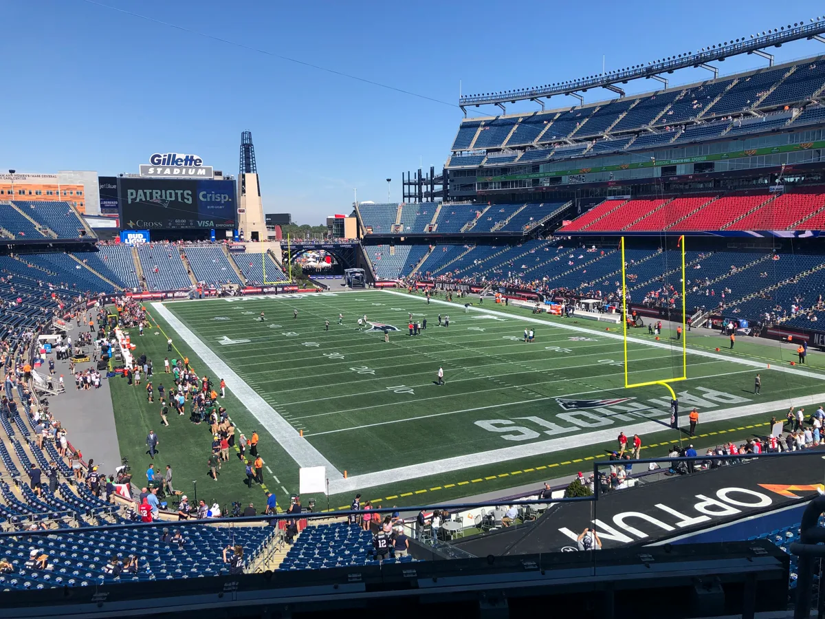 Gillette Stadium interior looking down at the green turf during pre-game warm-ups on a clear blue-sky day in Foxborough